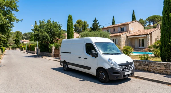 Photographie professionnelle d'une camionnette ou véhicule utilitaire blanc de service stationné dans une rue résidentielle du Var, face à une maison avec piscine. Le véhicule porte les marquages/logos visibles de l'entreprise pisciniste. La scène est prise de jour en milieu ensoleillé. L'arrière-plan montre l'environnement résidentiel typique du Var avec maisons, végétation méditerranéenne, et la piscine partiellement visible. L'image symbolise la proximité géographique du service d'intervention mobile et la couverture territoriale du Var, sans montrer d'action technique ni d'équipe en mouvement, se concentrant uniquement sur le vecteur de déplacement qui représente la mobilité et l'accessibilité de l'entreprise.