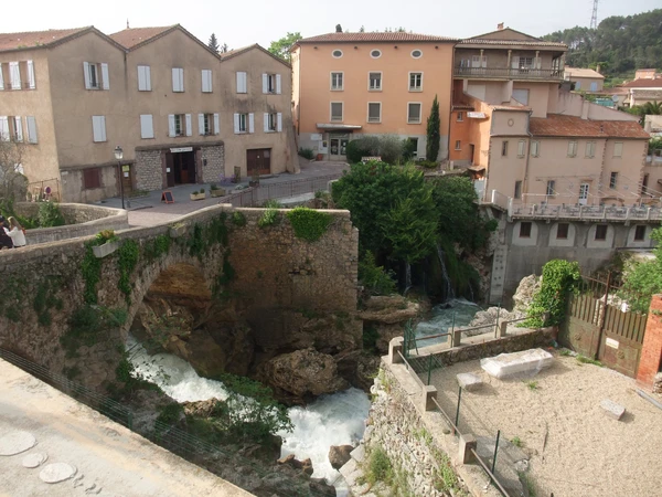 Une photographie professionnelle montrant une vue aérienne ou de trois-quarts d'une piscine résidentielle typique du Var dans son contexte d'implantation locale, avec la maison de style provençal et la terrasse visibles. La piscine doit être clairement le sujet central, bien entretenue et accueillante. L'image peut inclure des éléments du paysage varois (végétation méditerranéenne, architecture locale) pour contextualiser le territoire de couverture d'intervention. Cette perspective doit différer visuellement des images d'équipes en action lors d'interventions techniques, en montrant plutôt l'environnement résidentiel cible et la piscine comme patrimoine à maintenir.